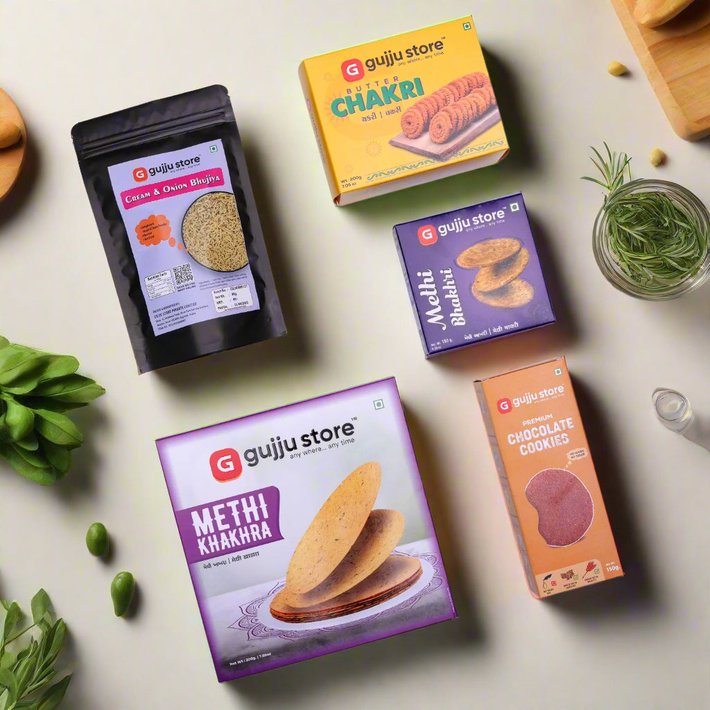 An assortment of six Gujju Store snack products arranged on a white background. The items include a purple box of Methi Khakhra, a yellow box of Butter Chakri, a purple box of Methi Bhakhri, an orange box of Premium Chocolate Cookies, a black pouch of Cream & Onion Bhujia, and all products are attractively packaged with colorful labels.