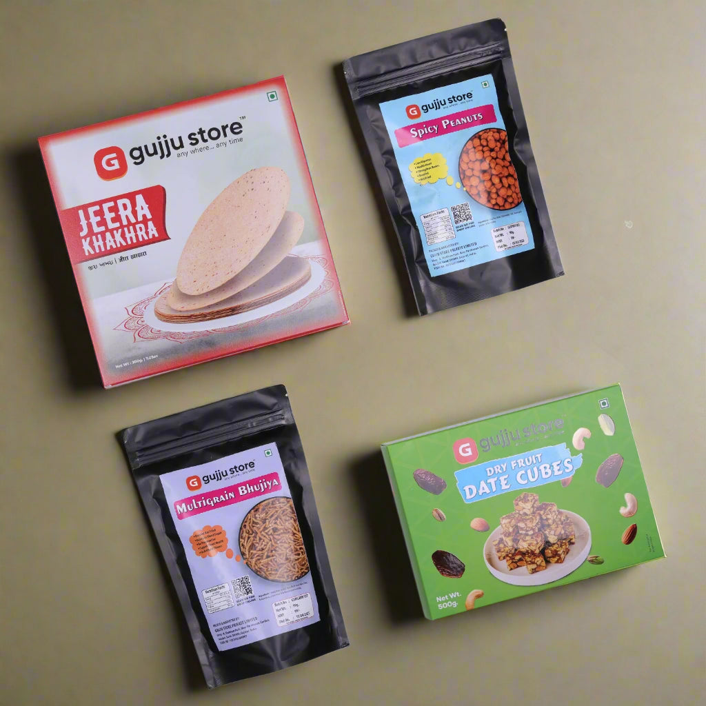 A photo of four packaged snack products from Gujju Store, arranged on a white background. The items include Jeera Khakhra in a red and white box, Spicy Peanuts in a black resealable pouch with a blue label, Multigrain Bhujia in a similar black pouch with a purple label, and Dry Fruit Date Cubes in a green box featuring dates and nuts around the product image.