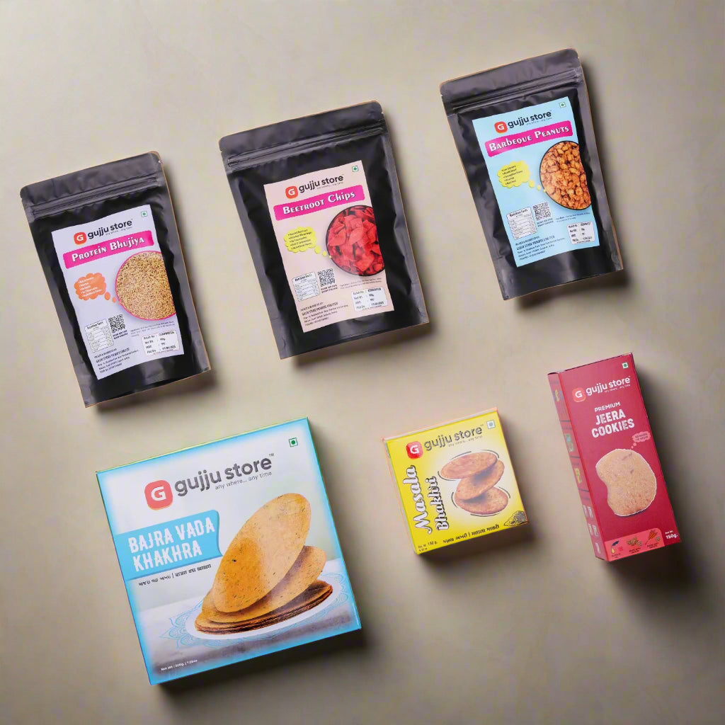 A display of six Gujju Store snack products on a white background. The items include three black pouches labeled Protein Bhujia, Beetroot Chips, and Barbeque Peanuts. Below them are three boxes: a blue box of Bajra Vada Khakhra, a yellow box of Masala Bhakhri, and a red box of Premium Jeera Cookies. Each product features vibrant packaging and clear branding.