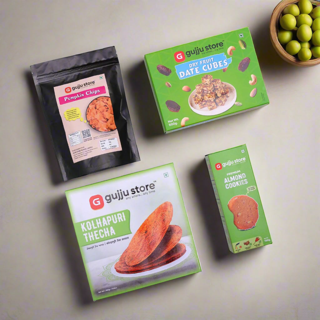 A display of five Gujju Store snack products on a white background. The items include a black pouch of Pumpkin Chips, a green box of Dry Fruit Date Cubes, a green and white box of Kolhapuri Thecha Khakhra, and a green box of Premium Almond Cookies. Each product is neatly packaged with colorful branding and clear labeling.